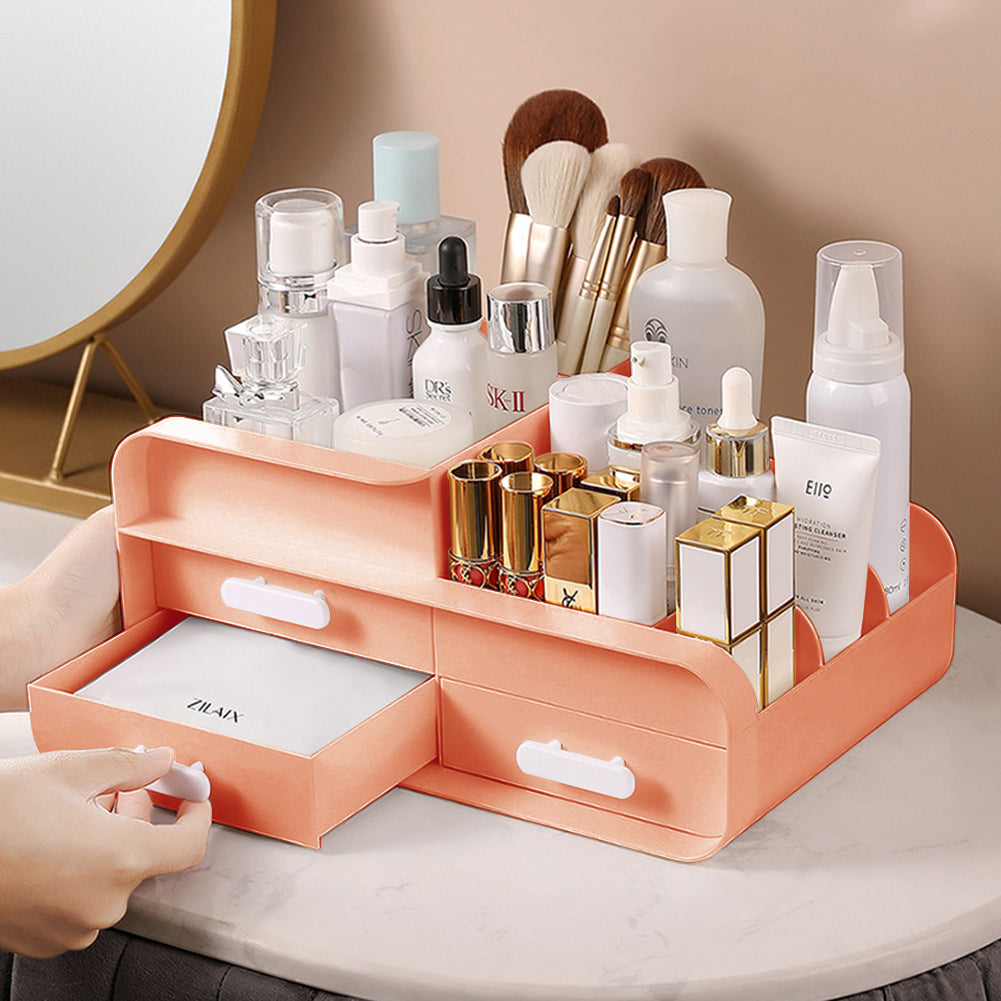 Peach-pink desktop organizer tray with open compartments and front drawers holding cosmetics